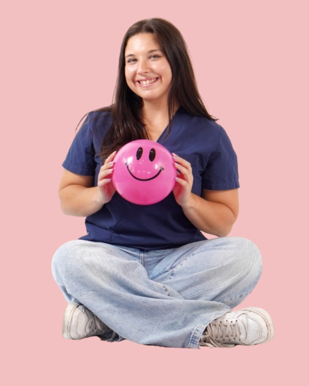 Licenciada en Psicomotricidad sonriendo y sosteniendo una pelota rosa con una cara feliz