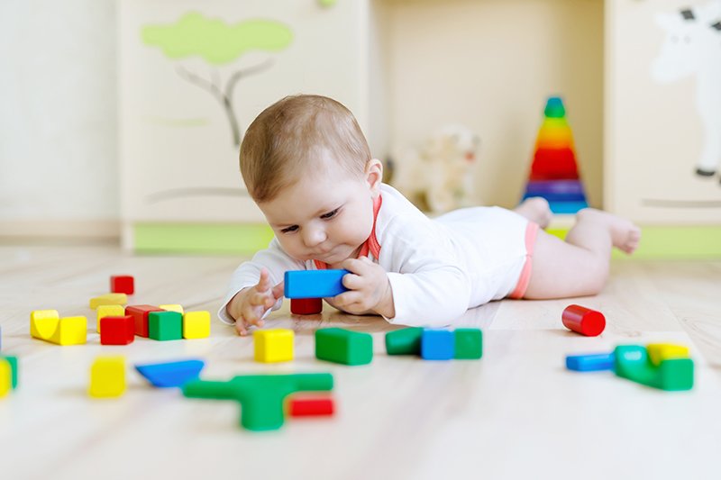 Bebé jugando de manera autónoma con piezas de colores